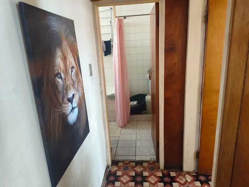 A view from a hallway looking into a bathroom featuring tiled flooring and dated interior finishes.