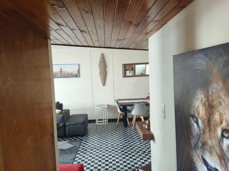 Open plan living and dining area featuring a distinctive timber ceiling and checkered floor tiles, offering a versatile space for daily living.