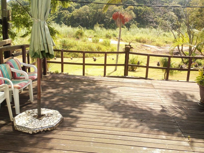 An elevated timber deck featuring a wooden balustrade, offering an open view of the surrounding garden and natural landscape.