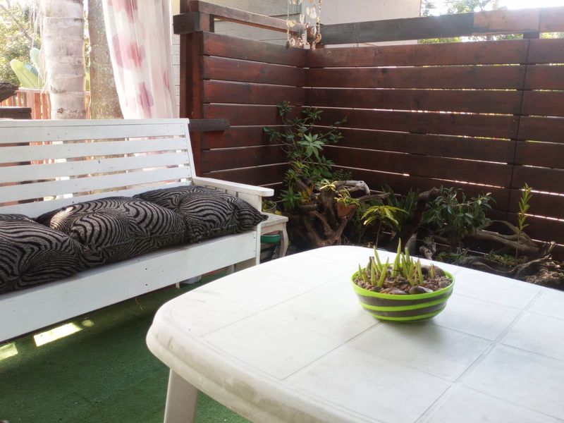 A covered outdoor patio area featuring a timber privacy screen and artificial turf flooring, providing a private space for relaxation.
