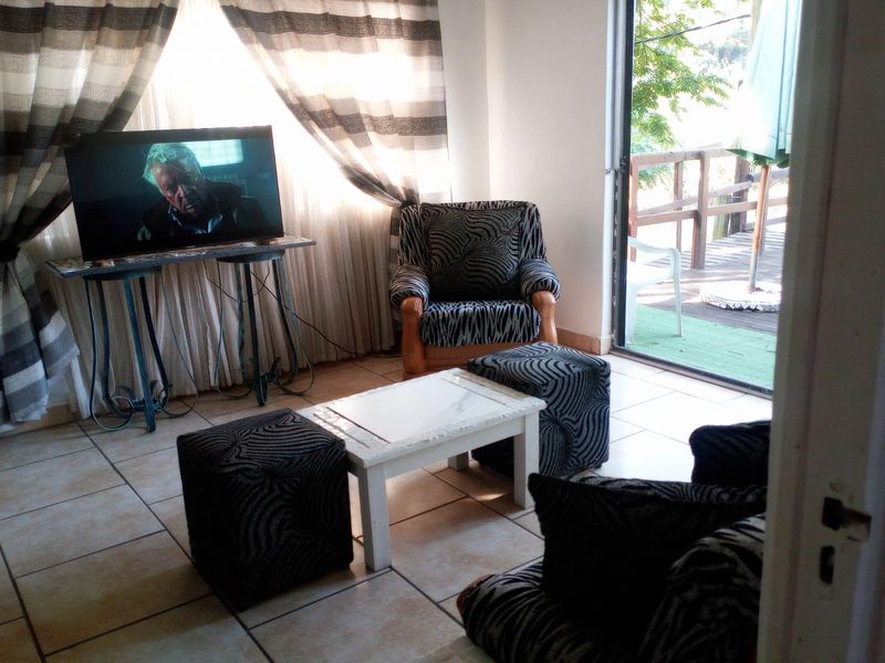 A living room area featuring tiled flooring and a sliding glass door providing access to an outdoor patio space.