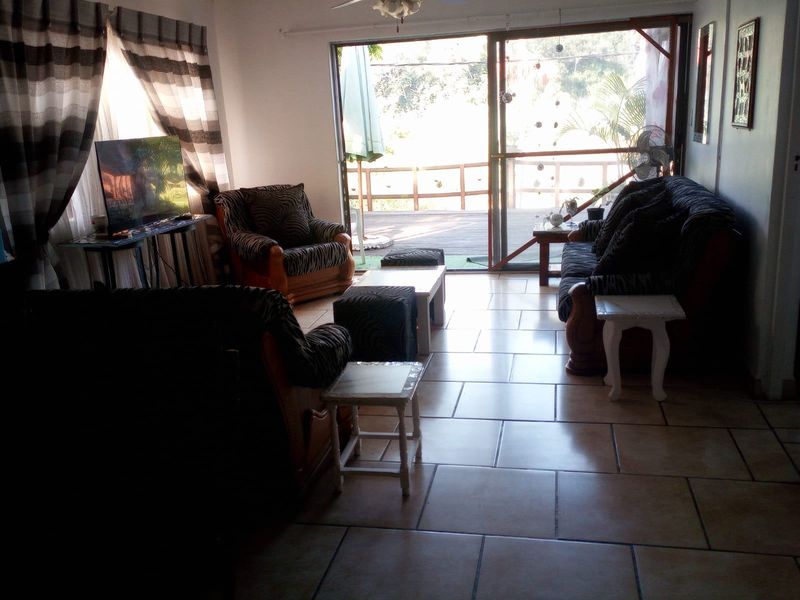 A living room featuring tiled flooring and a large sliding glass door providing direct access to an outdoor deck area.