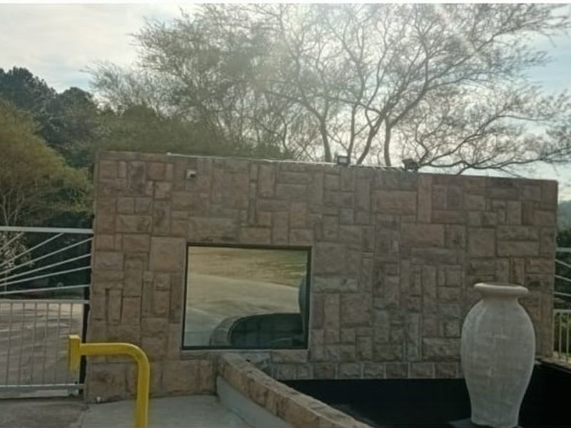 Front entrance area featuring stone-clad wall, security gate, and integrated water feature.