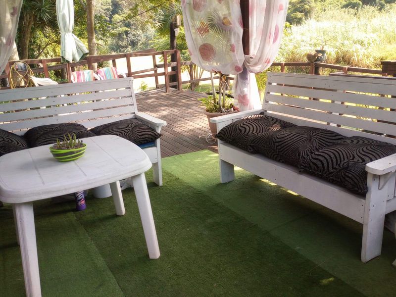 An outdoor patio area featuring timber decking and a wooden balustrade, overlooking a natural landscape.