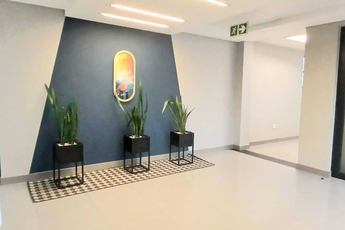 A modern, well-maintained commercial entrance lobby featuring tiled flooring, recessed lighting, and a glass-paneled door.