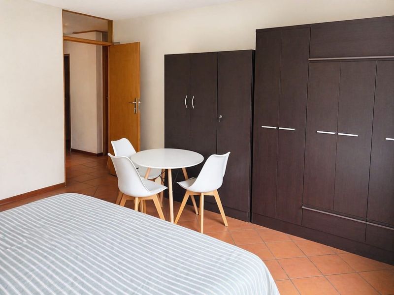 A bedroom featuring tiled flooring and dark built-in cupboards, providing functional storage space within the apartment.