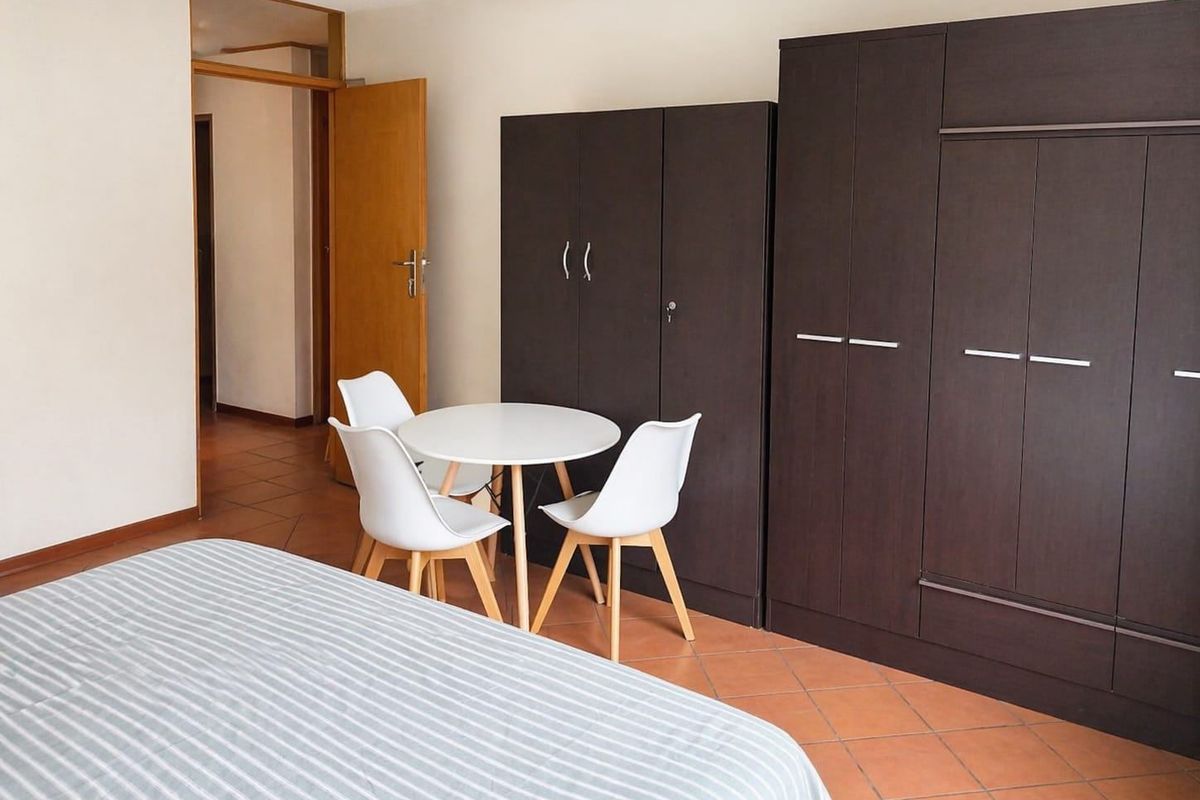 A bedroom featuring tiled flooring and dark built-in cupboards, providing functional storage space within the apartment.