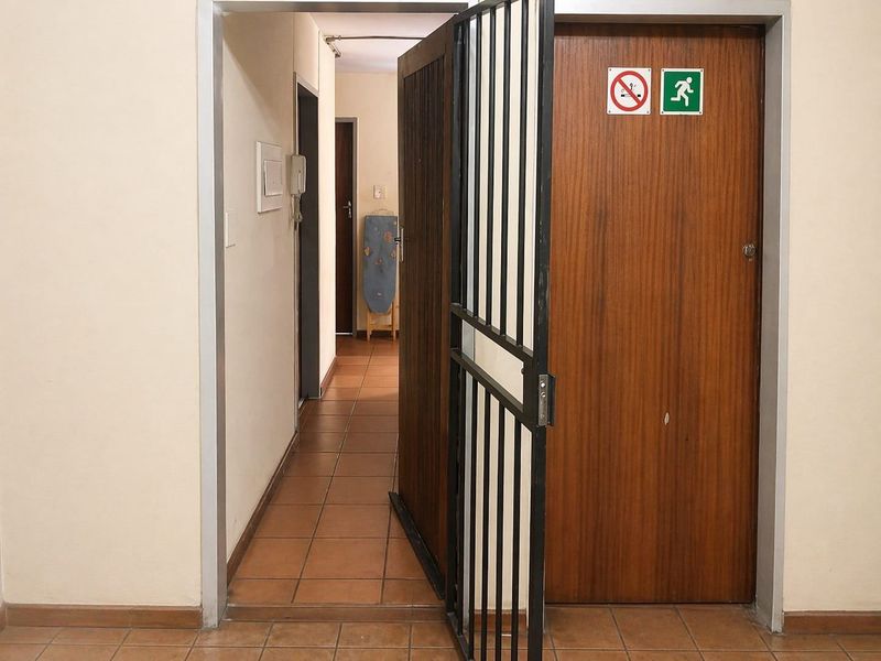 A functional apartment hallway featuring tiled flooring, a security gate, and an intercom system.
