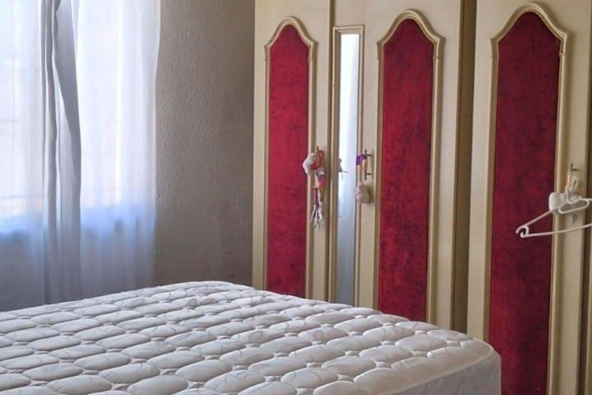 A bedroom featuring a built-in wardrobe with decorative red panels and a standard ceiling light fixture.