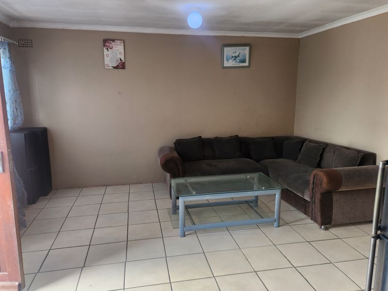 A living room featuring ceramic floor tiles and coved ceiling cornicing, providing a functional base for potential interior updates.