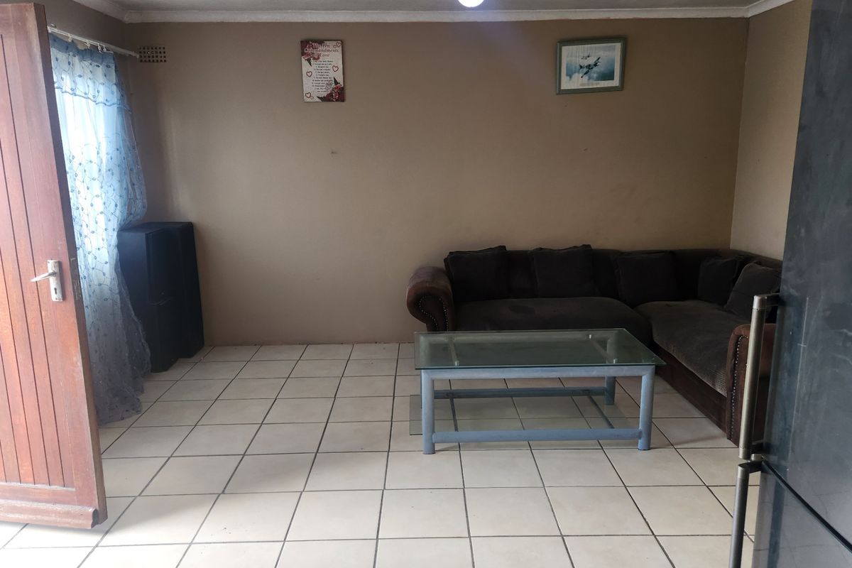 A living room featuring ceramic floor tiles, a timber entrance door, and neutral wall finishes, providing a functional base for interior updates.