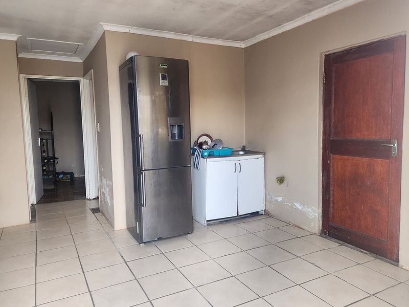 A small kitchen area featuring tiled flooring and a basic sink cabinet, currently showing signs of wear and requiring cosmetic maintenance.