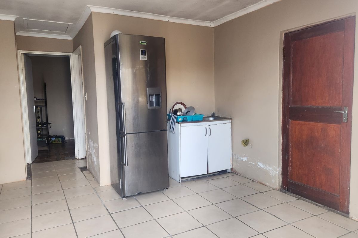 A small kitchen area featuring tiled flooring and a basic sink cabinet, currently showing signs of wear and requiring cosmetic maintenance.