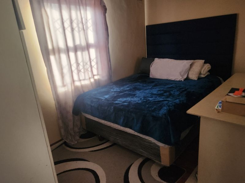 A compact bedroom featuring a window with a security gate and built-in storage space.