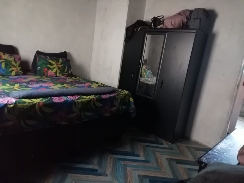 A bedroom featuring herringbone patterned flooring and unfinished wall surfaces, requiring cosmetic updates to improve the overall finish and aesthetic appeal.