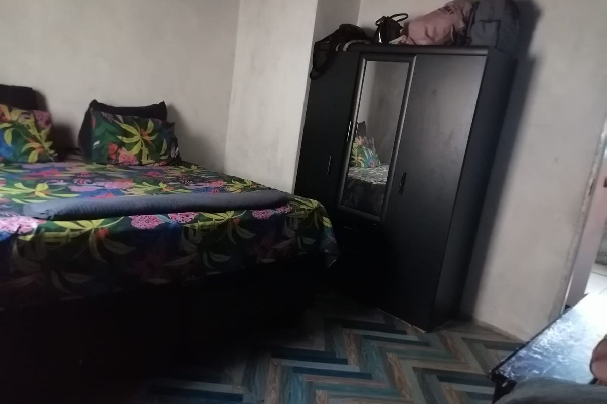 A bedroom featuring herringbone patterned flooring and unfinished wall surfaces, requiring cosmetic updates to improve the overall finish and aesthetic appeal.