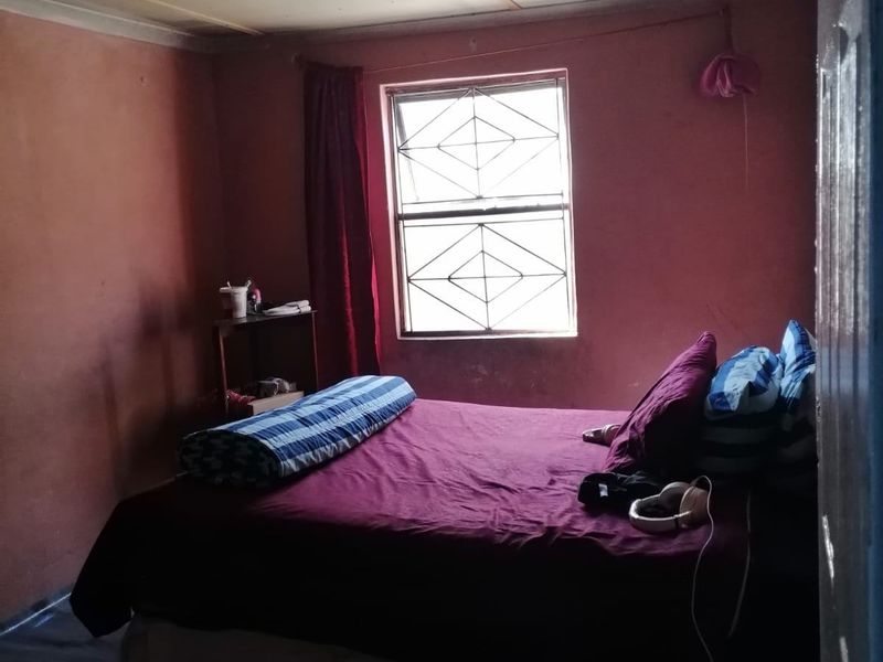 A bedroom featuring a window with security bars and coving, requiring cosmetic updates to the wall and ceiling finishes.