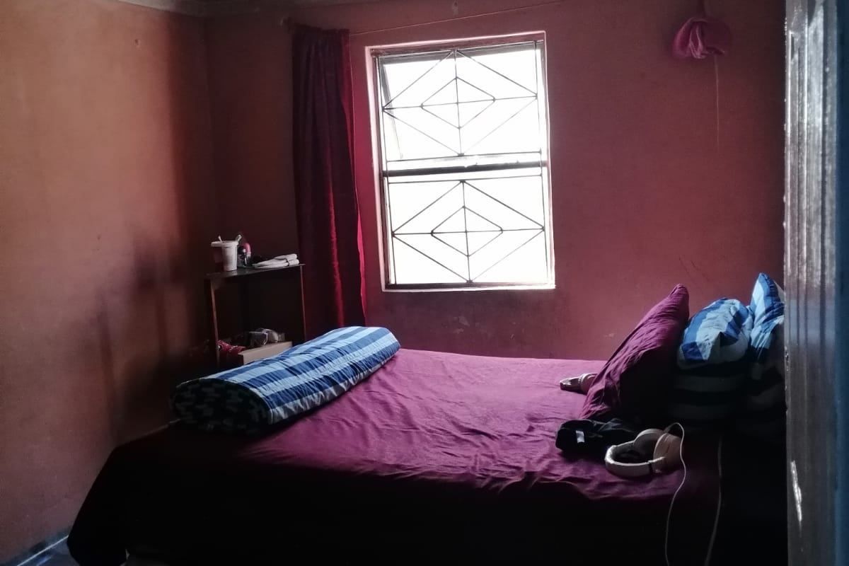 A bedroom featuring a window with security bars and coving, requiring cosmetic updates to the wall and ceiling finishes.