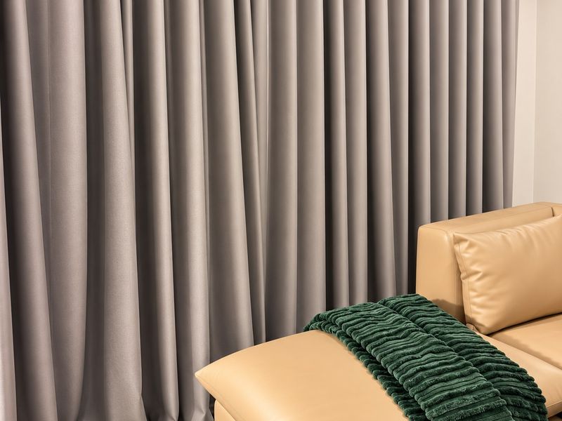 A living area featuring full-length grey curtains mounted on a dark track, providing a clean and modern aesthetic.