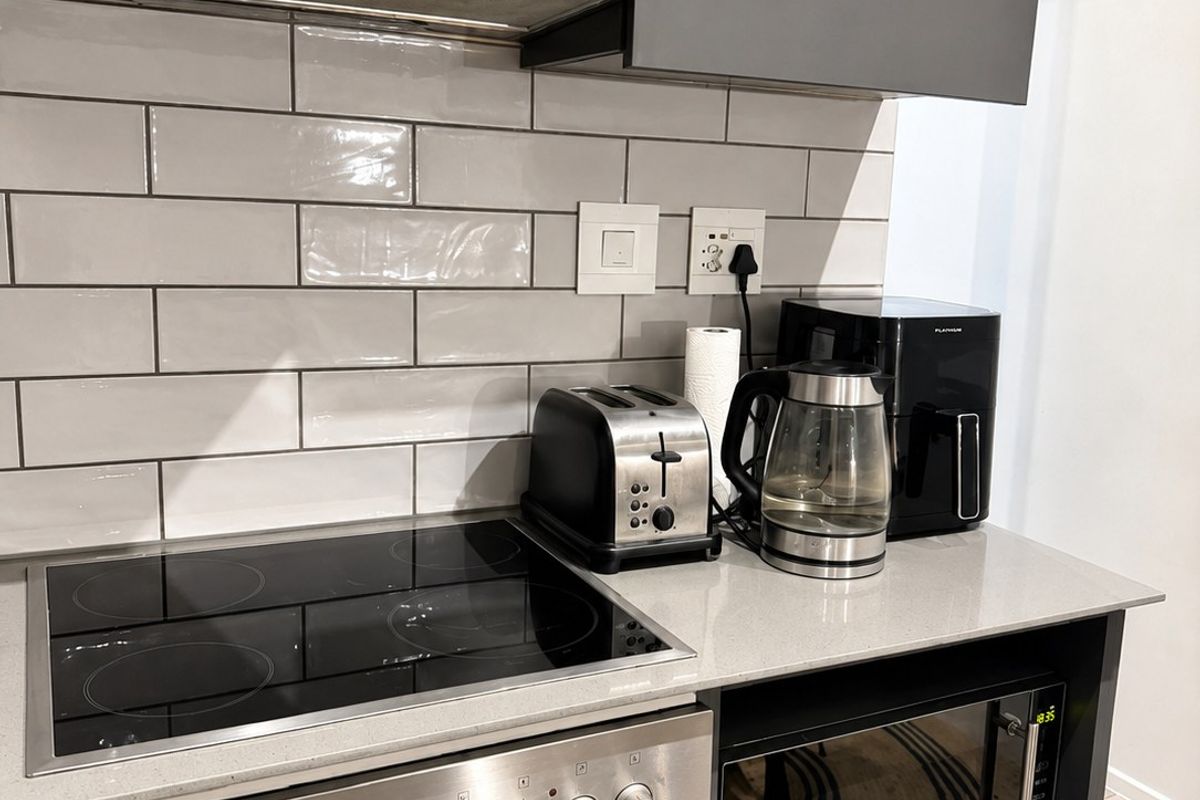 Modern kitchen featuring grey cabinetry, stone countertops, subway tile backsplash, and integrated Bosch extractor fan with built-in oven and microwave.