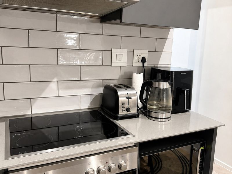 Modern kitchen featuring grey cabinetry, stone countertops, subway tile backsplash, and integrated Bosch extractor fan with built-in oven and microwave.