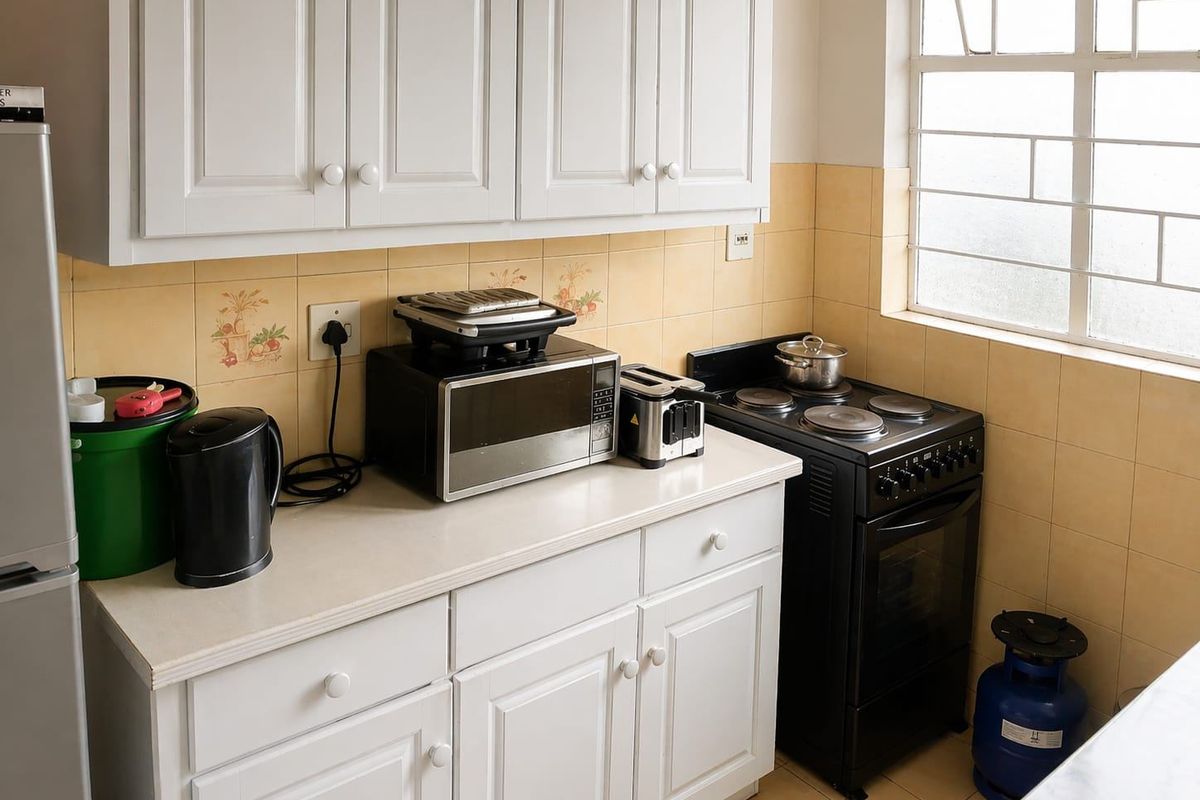 A functional kitchen featuring white cabinetry, tiled backsplash, and a freestanding stove, offering a practical layout with natural light from the window.