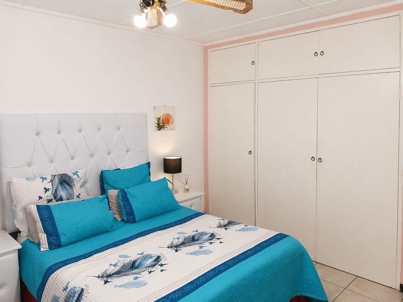 A bedroom featuring white built-in cupboards and a ceiling fan, providing functional storage and climate control.
