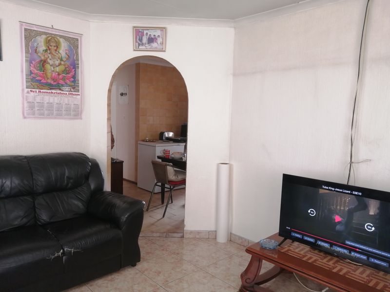 A living room featuring an arched doorway leading to an adjacent space, finished with ceramic floor tiles and coved ceilings.