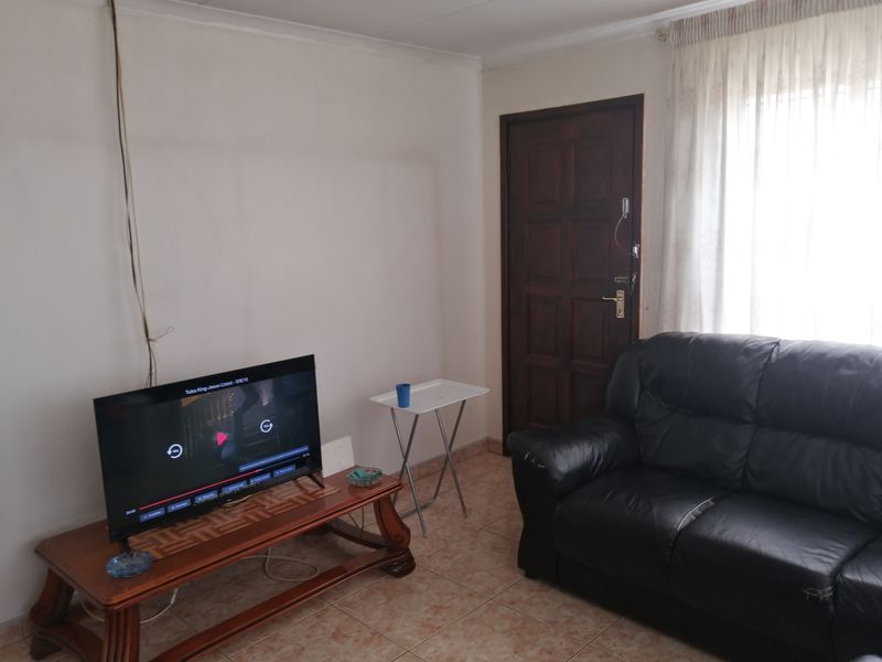 A living room area featuring tiled flooring and a traditional timber door, requiring minor maintenance to address exposed wiring.