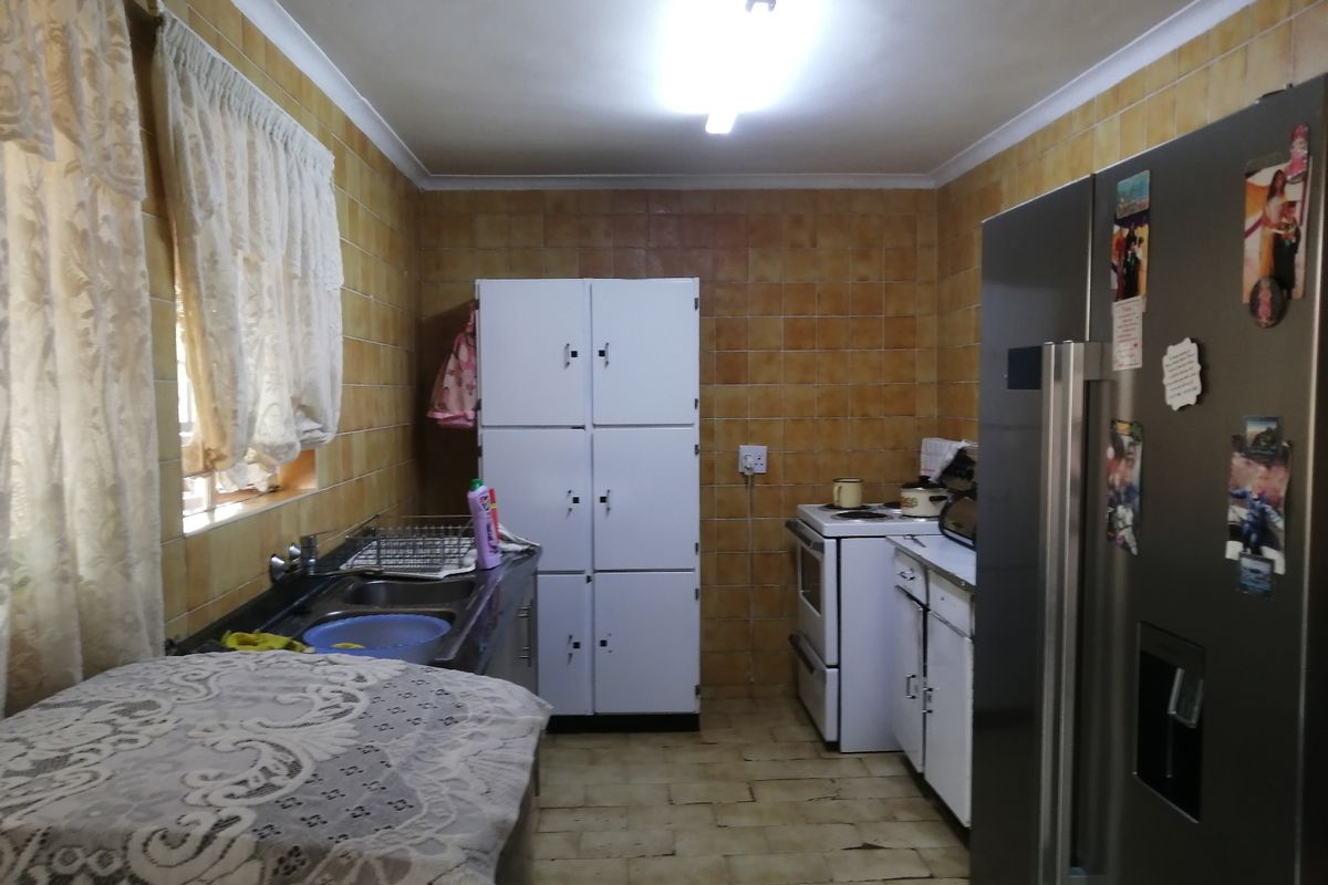 A functional kitchen featuring tiled walls and flooring, equipped with a double sink and built-in cabinetry, offering potential for a modern renovation.