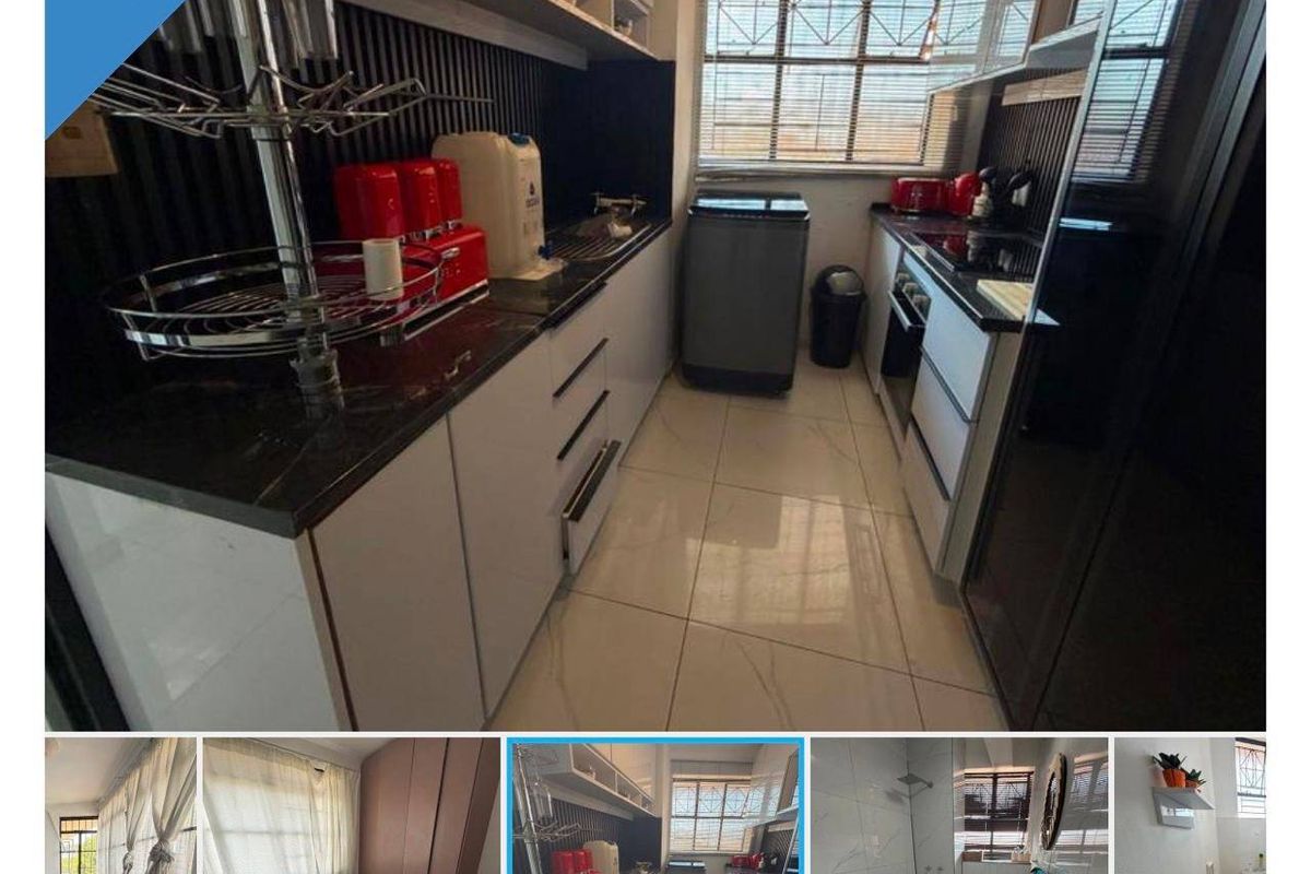 A compact, modern kitchen featuring sleek white cabinetry, dark granite countertops, built-in oven, and tiled flooring with security bars on the window.