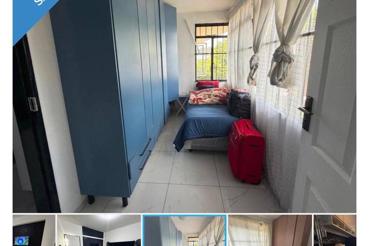 A bedroom featuring built-in blue cabinetry and tiled flooring, with large windows providing natural light.