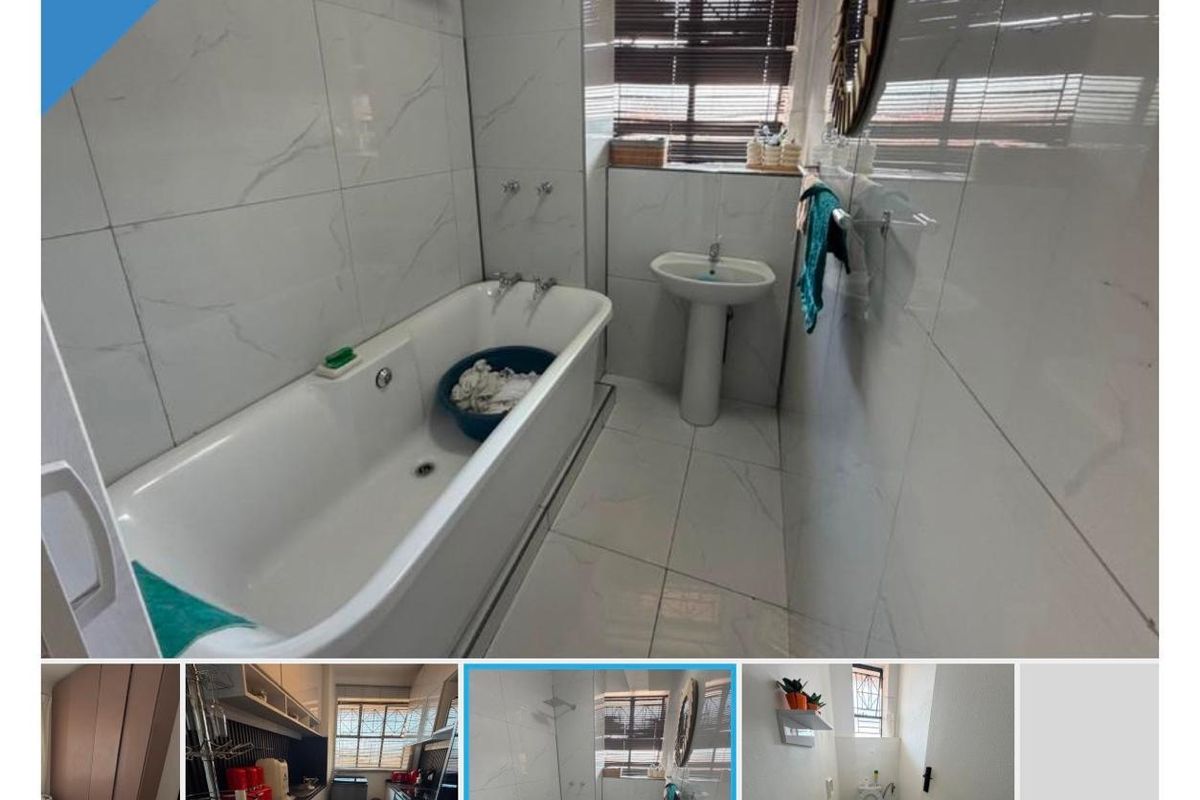 A bathroom featuring white marble-look wall tiles, a bathtub with a shower head, and a pedestal basin.