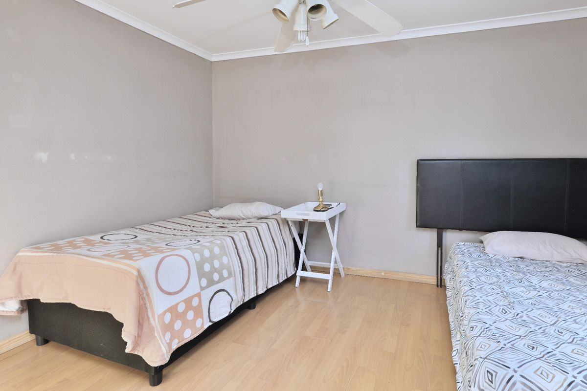 A bedroom featuring light wood-look laminate flooring, neutral wall tones, and a ceiling fan.