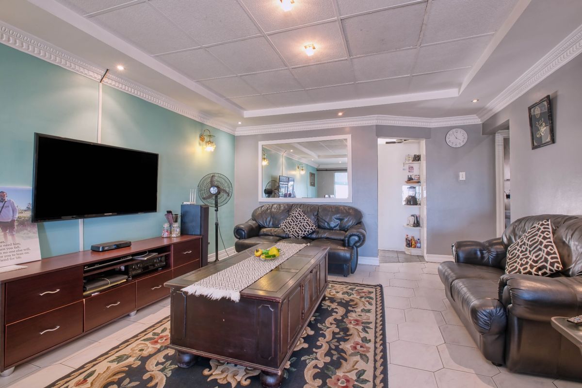 A living room featuring tiled flooring, decorative crown molding, and a built-in wall mirror.