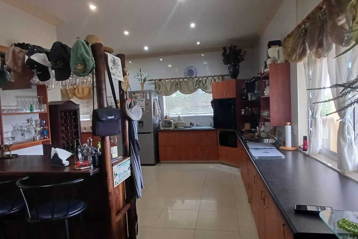 Spacious kitchen featuring extensive wooden cabinetry, dark laminate countertops, built-in double wall ovens, and tiled flooring with recessed lighting throughout.