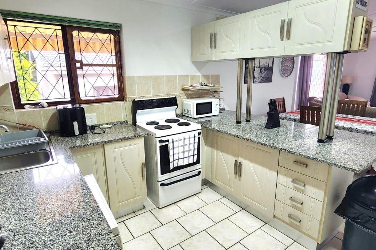 A functional kitchen featuring granite countertops, tiled flooring, and a breakfast bar, seamlessly connecting to the adjacent living and dining area.