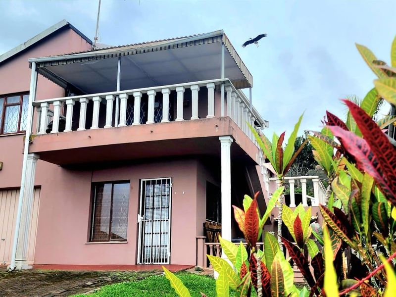 Front exterior view of a townhouse featuring a garage, a covered upper-level balcony with balustrades, and a security gate entrance.