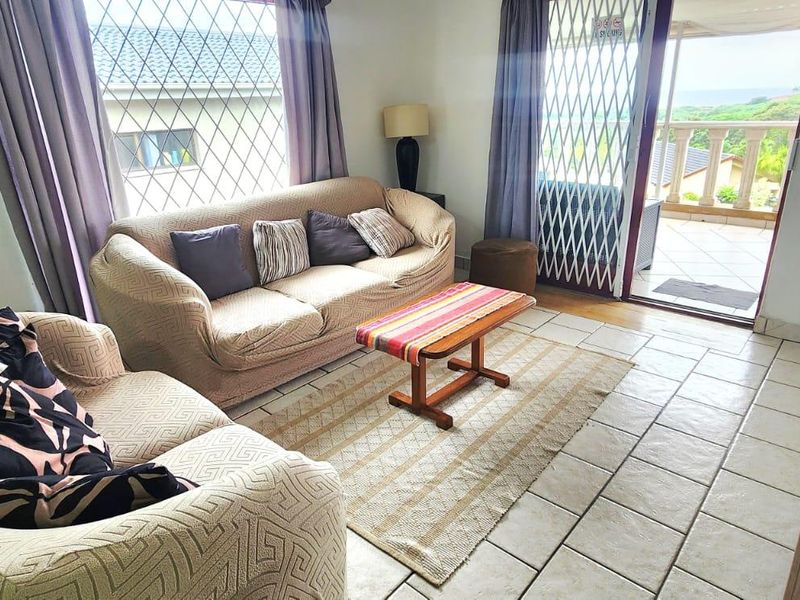 A living room featuring ceramic floor tiles, a security gate, and a sliding glass door providing access to an outdoor balcony area.