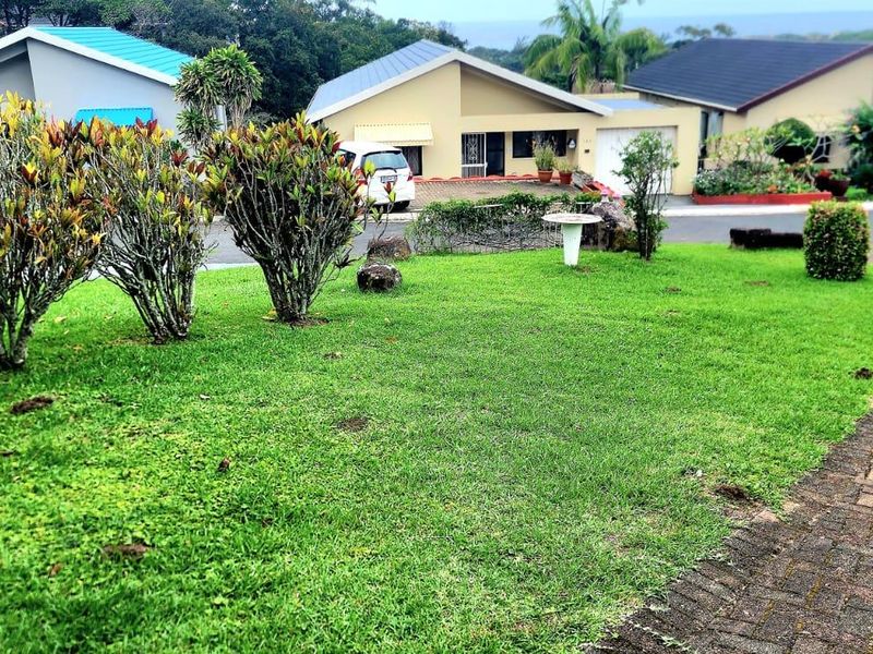 A view of the front garden and paved driveway leading towards the townhouse entrance in a residential estate setting.