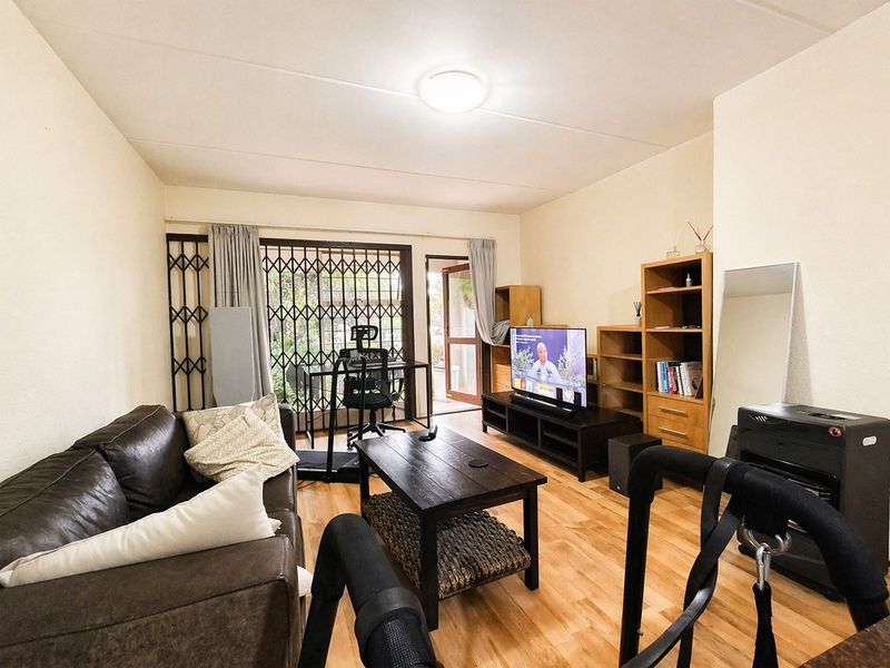 A living room featuring laminate flooring, a security gate, and a sliding door leading to an outdoor area.