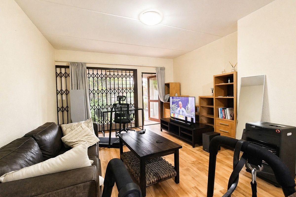 A living room featuring laminate flooring, a security gate, and a sliding door leading to an outdoor area.