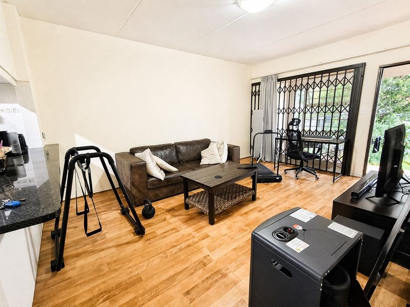 Open plan living area featuring laminate flooring, a kitchen counter, and a security gate leading to the exterior.