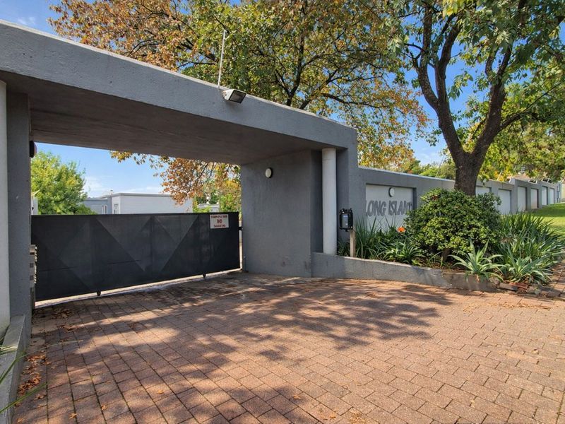 The entrance to the Long Island complex features a secure gated access point with a paved driveway and concrete architectural structure.