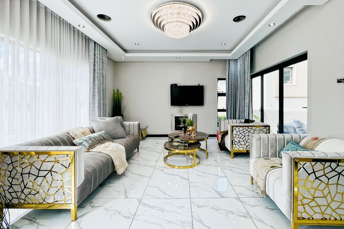 Modern living room featuring high-gloss marble-look floor tiles, a sophisticated recessed ceiling with a crystal chandelier, and a built-in fireplace.