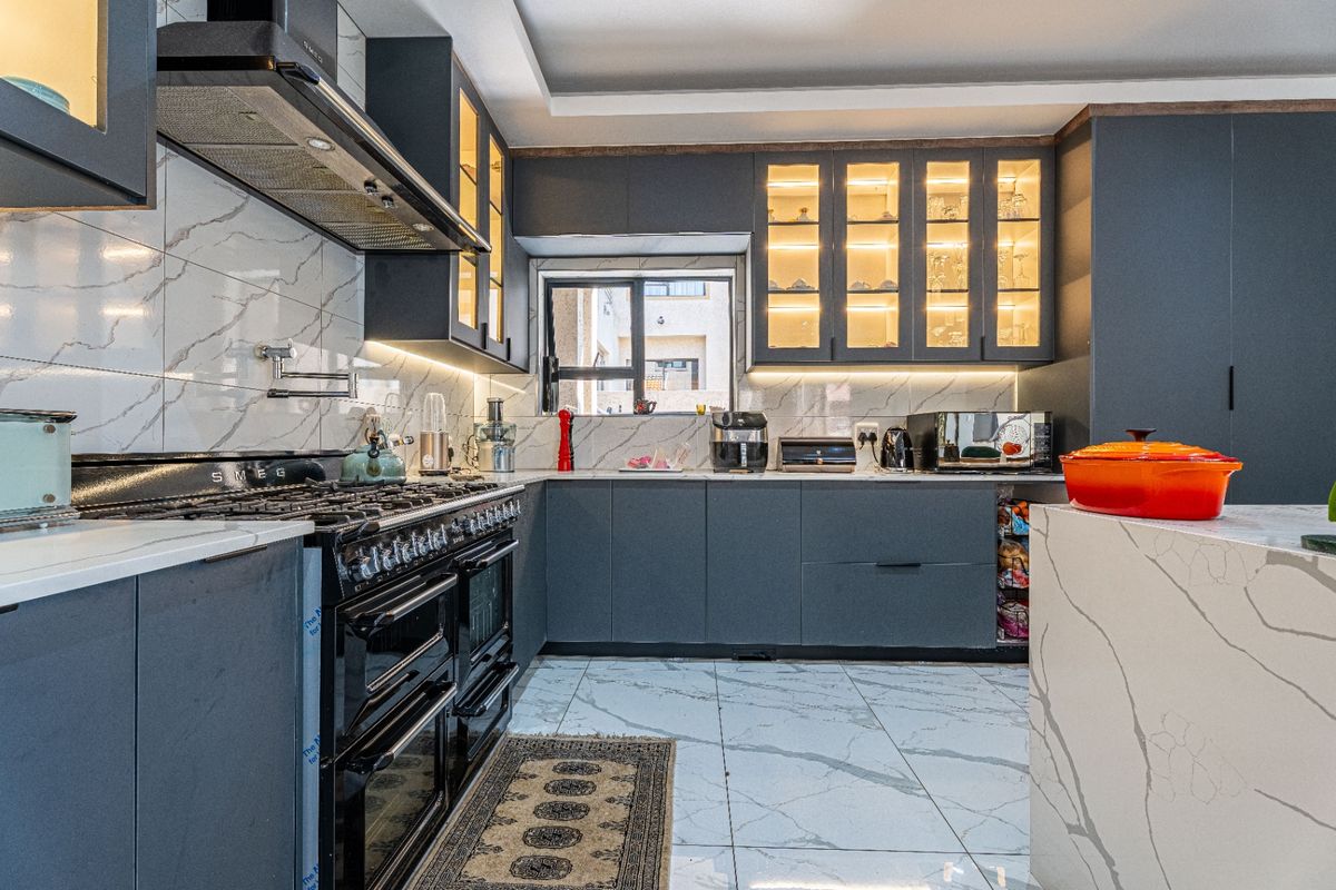 Modern kitchen featuring dark cabinetry, marble-look quartz countertops, high-end Smeg range cooker, integrated lighting, and premium tiled finishes throughout.