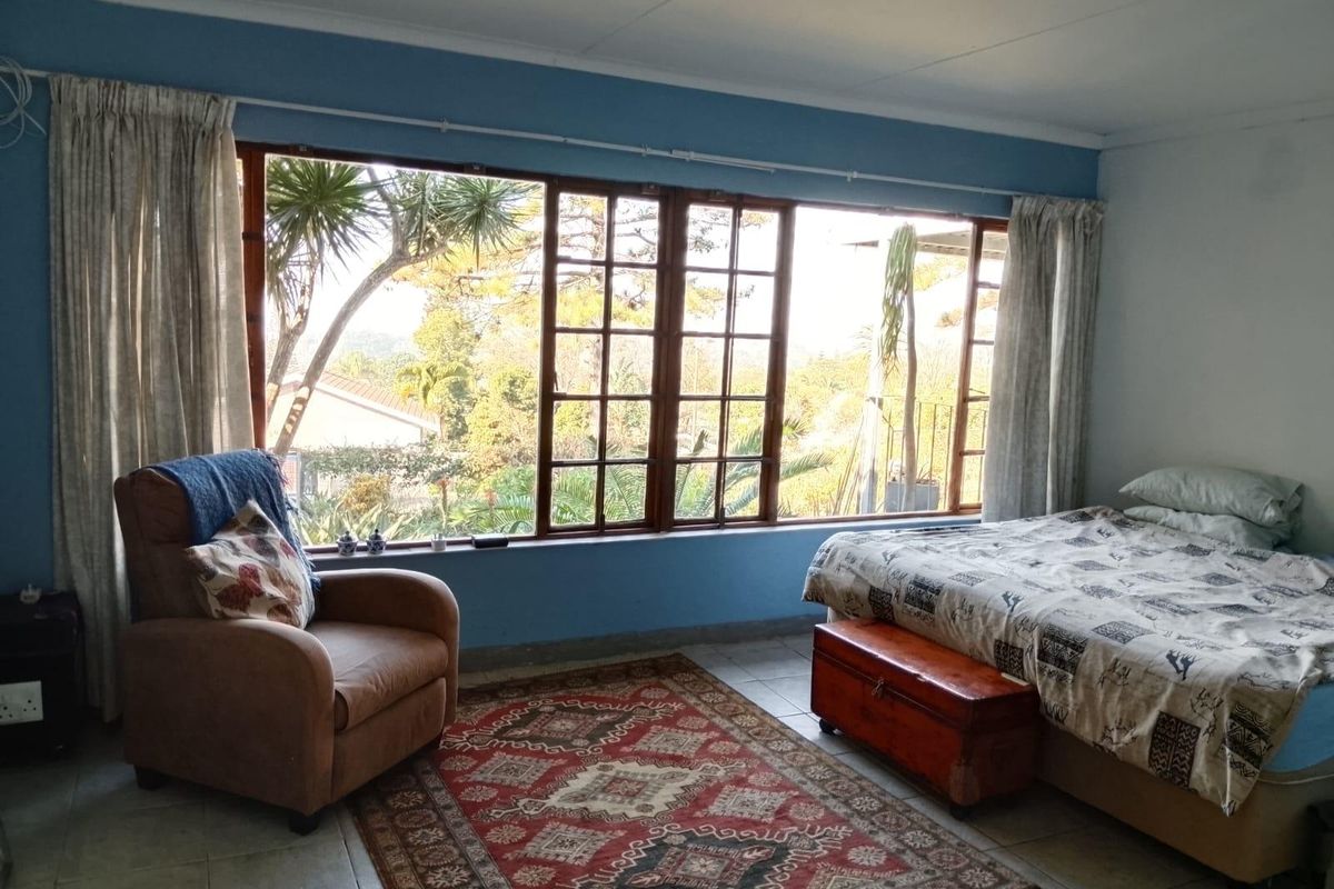 A bedroom featuring large timber-framed windows that provide natural light and views, complemented by tiled flooring.