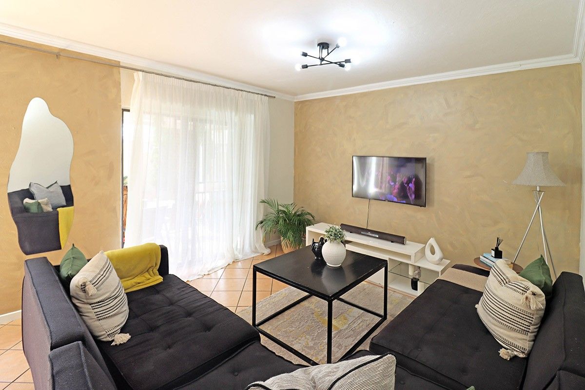 A comfortable living room featuring tiled flooring, crown molding, and a sliding glass door that provides access to the outdoor area.