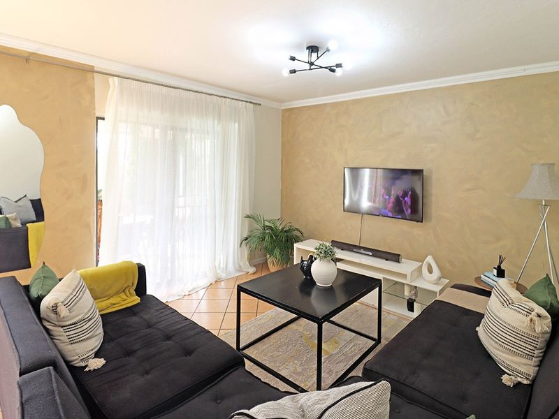 A comfortable living room featuring tiled flooring, crown molding, and a sliding glass door that provides access to the outdoor area.