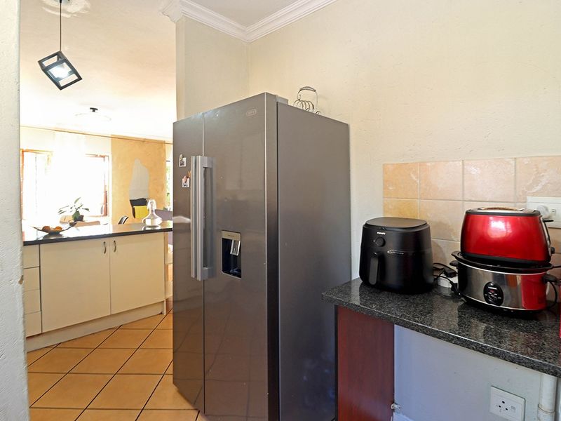 A functional kitchen area featuring granite countertops, tiled backsplash, and ceramic tile flooring, with an open-plan layout leading to the adjacent living space.